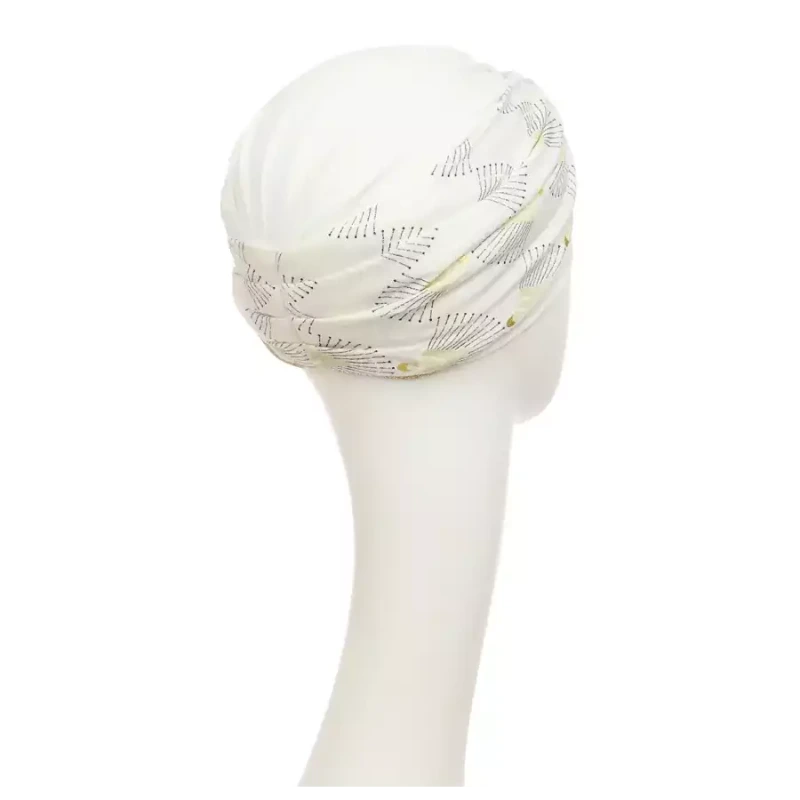 Shakti Turban Printed, Ivory w/Peacock. Its base is white, while the beautiful band features an elegant linen peacock print. It features beautiful peacock details in black and shiny gold and a fine gold trim, making it a very elegant and flattering turban.
