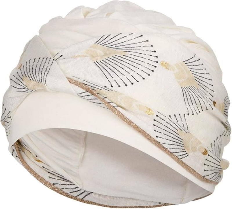 Shakti Turban Printed, Ivory w/Peacock. Its base is white, while the beautiful band features an elegant linen peacock print. It features beautiful peacock details in black and shiny gold and a fine gold trim, making it a very elegant and flattering turban.
